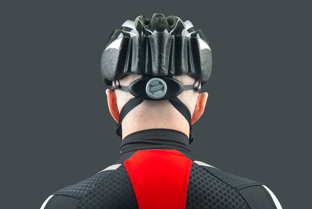 Male cyclist in a bicycle helmet from the back on a dark background - Foto, Imagem