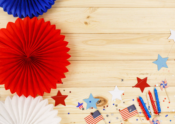 Decoraties voor de 4 juli dag van de Amerikaanse onafhankelijkheid, vlag, kaarsen, rietjes, papier fans. USA vakantie decoraties op een houten achtergrond, bovenaanzicht, platte lay - Foto, afbeelding