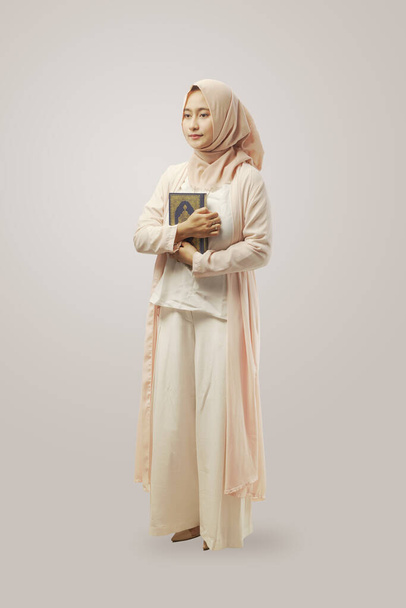 Portrait of Young Muslim woman wearing hijab  holding a holy Qur'an isolated white background - Fotoğraf, Görsel
