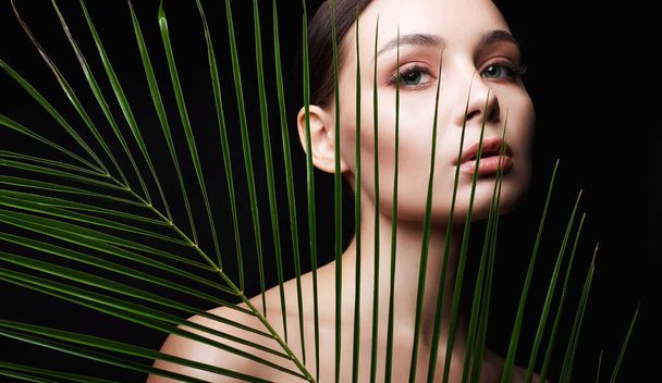 beautiful girl with palm leaves. Beautiful young woman. Beauty Portrait. Natural cosmetics - Photo, Image