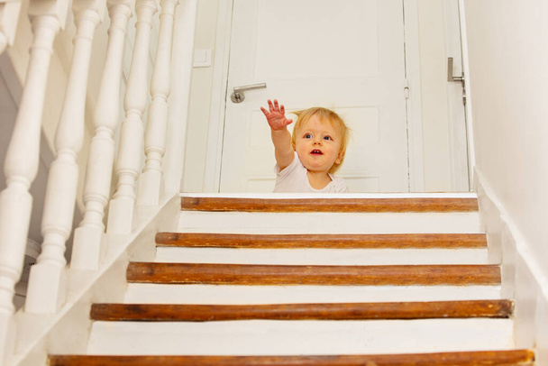 Scary little toddler boy sit and scream on top of stairs afraid of height stretch hand for help - Fotó, kép