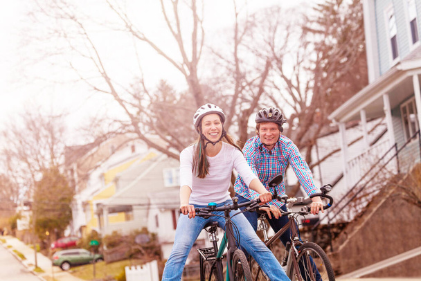 Laughing couple with smiling young woman ride a bicycle on the urban street wearing helmets - Foto, Imagem