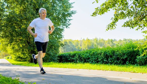 Aktív felnőtt férfi fut a parkban a reggeli edzés tavaszán. - Fotó, kép