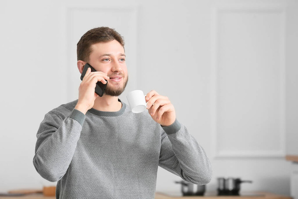 Handsome man talking by mobile phone in kitchen - Photo, Image