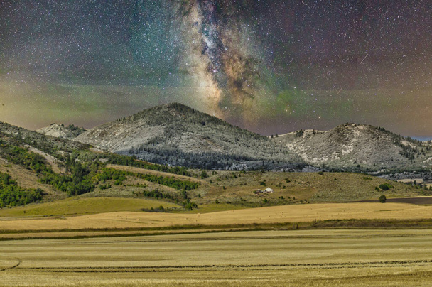 The milky way in a starry night sky above mountains - Фото, изображение