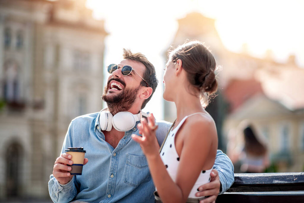 A fiatal pár szórakozik a városban, zenét hallgatnak és kávét isznak.. - Fotó, kép