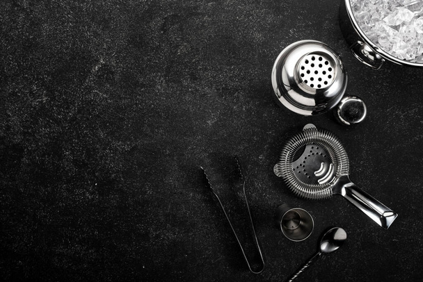 Steel bar tools and accessories for making cocktail. Shaker, jigger, strainer, spoon, tongs, muddler. Alcohol drink and beverages preparation concept. Black background, top view, copy space - Fotoğraf, Görsel
