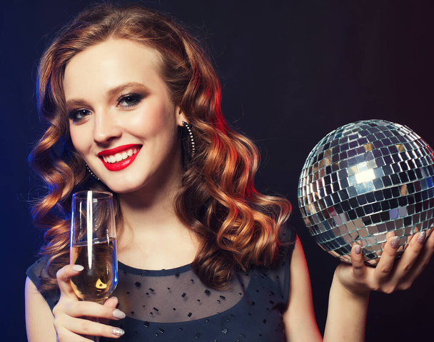 young woman holding a glass of wine and disco ball at night club - Фото, изображение