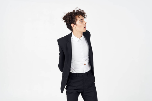handsome guy with curly hair and in a jacket posing in studio - Φωτογραφία, εικόνα