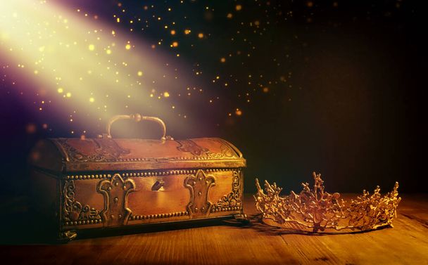 low key image of beautiful queen or king crown over gold treasure chest. vintage filtered. fantasy medieval period - Foto, afbeelding