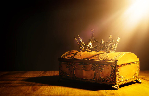 low key image of beautiful queen or king crown over gold treasure chest. vintage filtered. fantasy medieval period - Foto, Bild