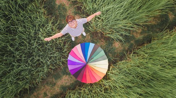 Asian woman and rainbow umbrella in grass meadow rice field from top view. - Photo, Image