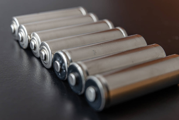 Batteries arranged side by side, on a dark surface. Batteries, energy and respect for the environment. Alkaline or rechargeable batteries. - Photo, Image