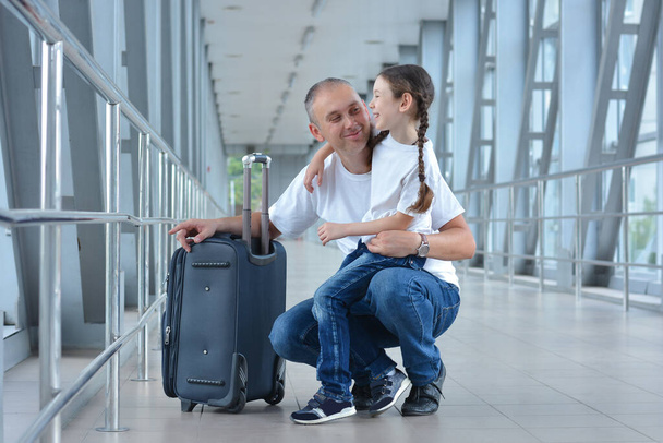 Ευτυχισμένος πατέρας και κόρη είναι έτοιμοι να επιβιβαστούν ή να συναντήσουν κάποιον στο αεροδρόμιο.. - Φωτογραφία, εικόνα
