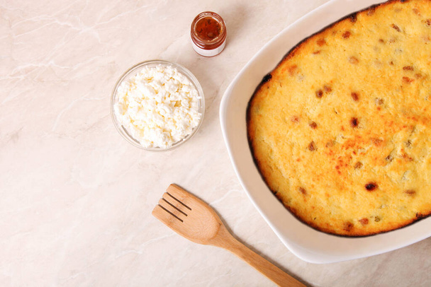 Cottage cheese casserole in a baking dish with ingredients on marble background. - Photo, Image