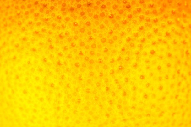 Закрыть фотографию текстуры грейпфрутовой кожуры. Экзотический спелый фруктовый фон, макровид. - Фото, изображение