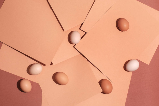 Regular chicken eggs from store on pinkish paper background  - Foto, Imagen