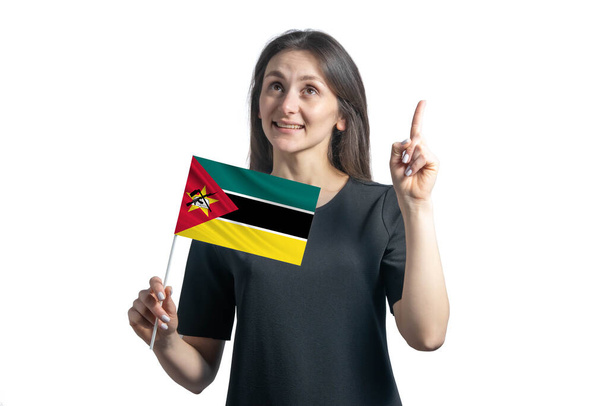 Happy young white woman holding flag of Mozambique and points thumbs up isolated on a white background. - Photo, Image