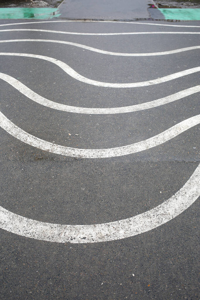 Witte zigzag strepen op het natte asfalt. Verticaal ingelijst schot. - Foto, afbeelding