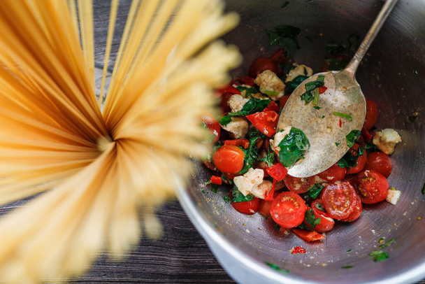Bardakta çiğ spagetti ve sarımsaklı bir kase domates, mozarella ve fesleğen.. - Fotoğraf, Görsel