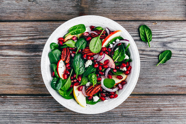 Green spinach salad with apples, feta cheese, pomegranate seeds, red onion and pecan nuts. Healthy eating. - Photo, Image