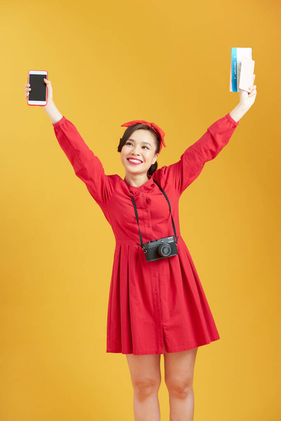 Image of excited young pretty woman tourist posing isolated over yellow wall background holding passport with tickets  - Foto, Imagem