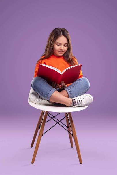 Girl reading book on chair - Фото, зображення