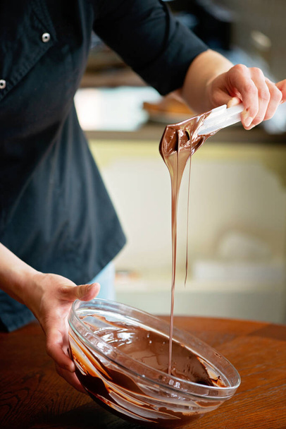 Pastry chef tempering hot dark chocolate. Cooking desserts. Soft selective focus. - Foto, immagini