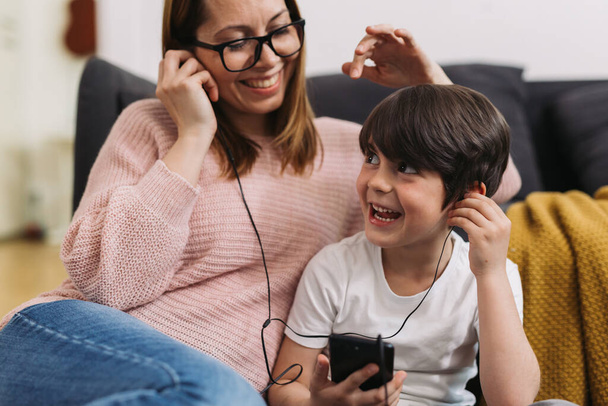 close up of mother and child listening music on headphones using smartphone - Valokuva, kuva