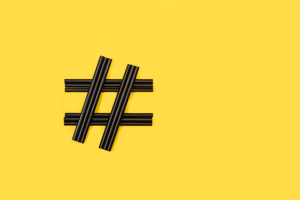 Cartel de hashtag hecho con paja de plástico negro sobre un fondo amarillo - Foto, imagen