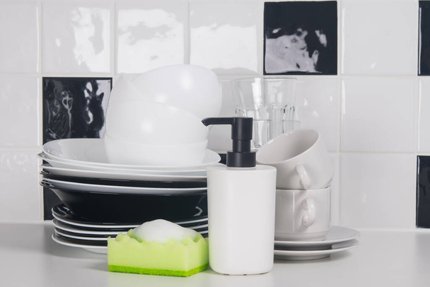 on the table,against the background of black and white tiles, washed dishes, plates, mugs, and on the sponge foam for disinfection - Valokuva, kuva
