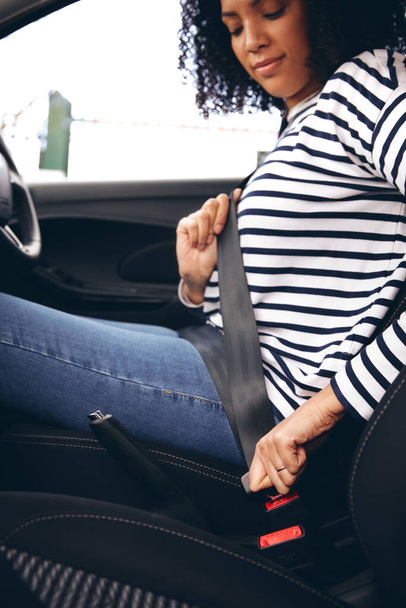 Close up of female driver in car fastening seatbelt at start of journey - Fotoğraf, Görsel