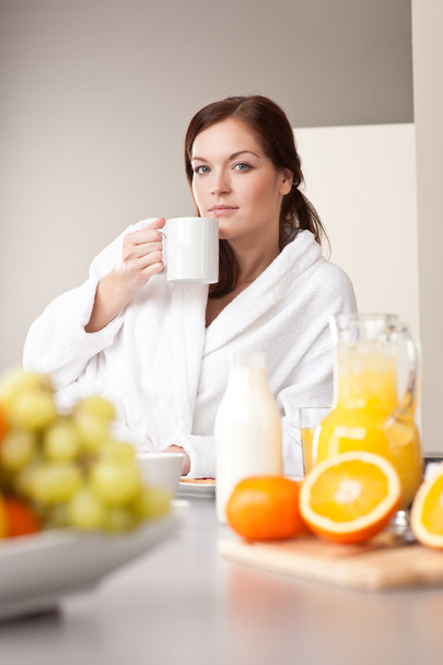 Молодая женщина наслаждается кофе и завтрак на кухне
 - Фото, изображение