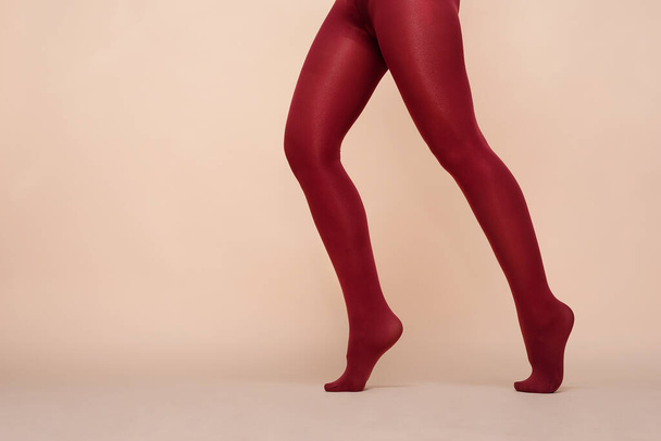 Women legs in the red color stockings on a light background. - Photo, image