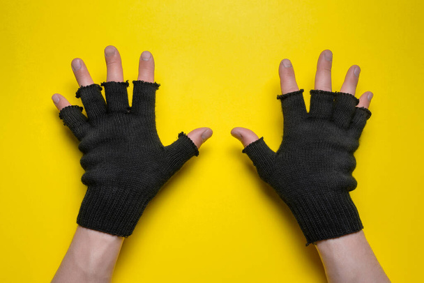 Hands in black gardening gloves on the yellow top view background. - Foto, imagen