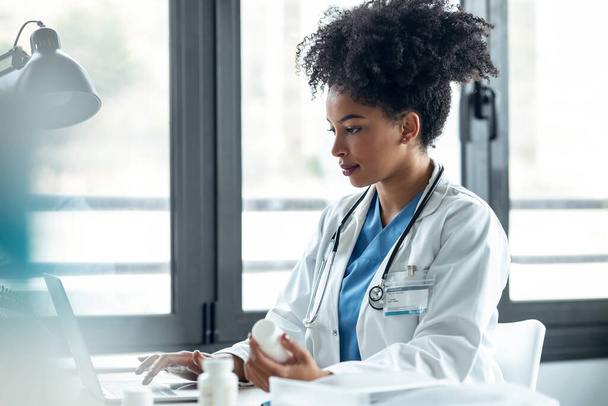Shot of attractive afro female doctor talking while explaining medical treatment to patient through a video call with computer in the consultation. - 写真・画像