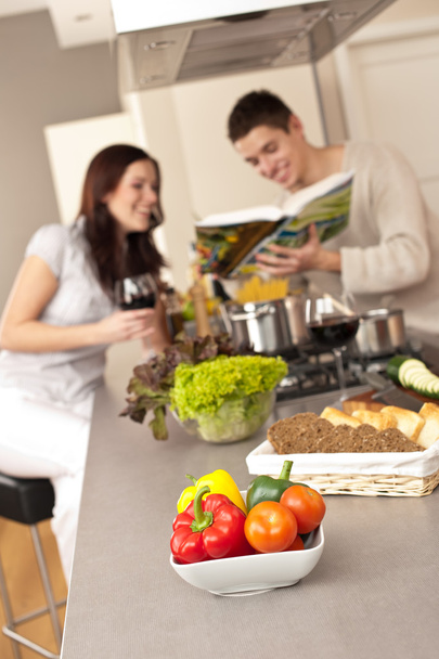Young couple in kitchen choosing recipe from cookbook drinking red wine - Φωτογραφία, εικόνα