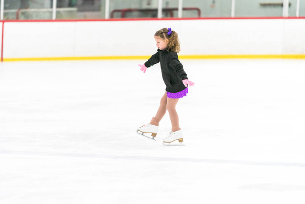 A kislány műkorcsolyázik egy korcsolyapályán. - Fotó, kép