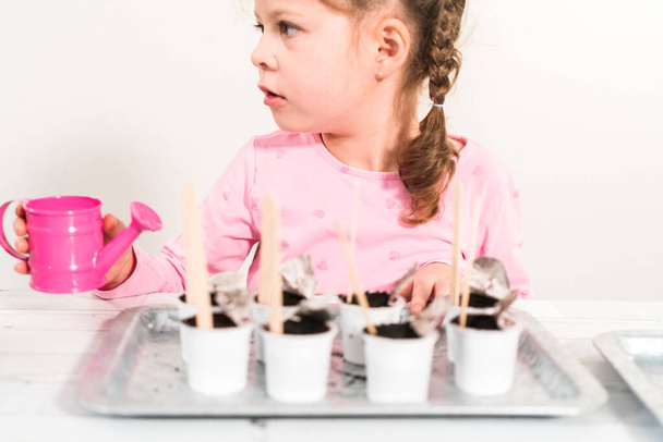 Kleines Mädchen pflanzt Samen in Kaffeepads, um einen Indoor-Gemüsegarten anzulegen. - Foto, Bild