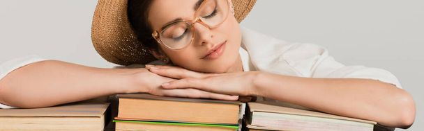 young woman in straw hat and glasses leaning on pile of books isolated on white, banner - Photo, Image