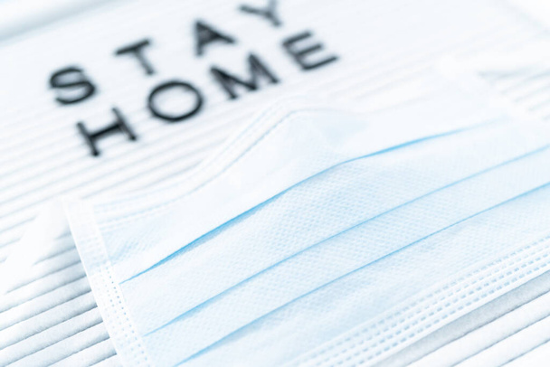 STAY HOME podepsat na nástěnku s modrou lékařskou maskou. - Fotografie, Obrázek