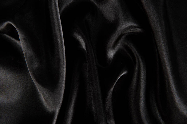 Fondo de textura de tela de seda negra abstracta. Onda suave de tela. Los pliegues del satén - Foto, imagen