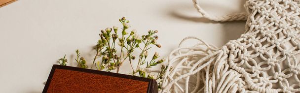растения в книге с твердой обложкой рядом вязаный мешок для перекрещивания тела на белом, баннер - Фото, изображение