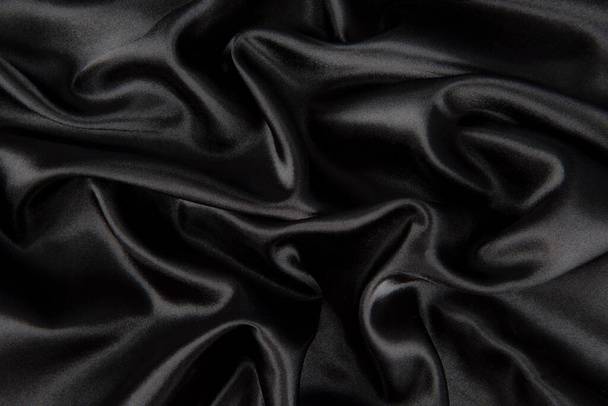 Abstract black silk fabric texture background. Cloth soft wave. Creases of satin - Фото, изображение