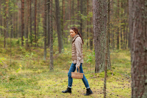 young woman picking mushrooms in autumn forest - Foto, afbeelding