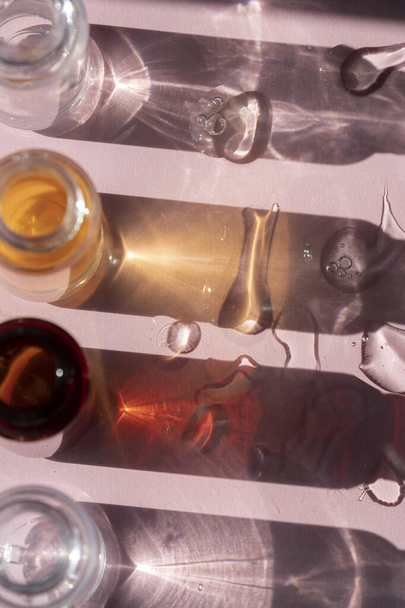 Serum şişelerinin gölgeleri ve yüz serumu damlaları - Fotoğraf, Görsel