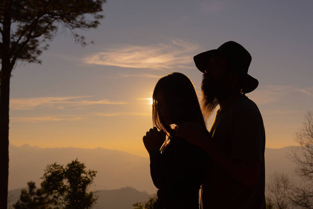 A fiatal pár élvezi a naplementét a hegyekben. - Fotó, kép
