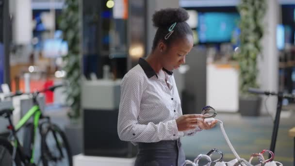 jonge moderne vrouw is winkelen in digitale apparatuur winkel, het bekijken van nieuwe model van smartwatch, het nemen van monster van demonstratie showcase - Video