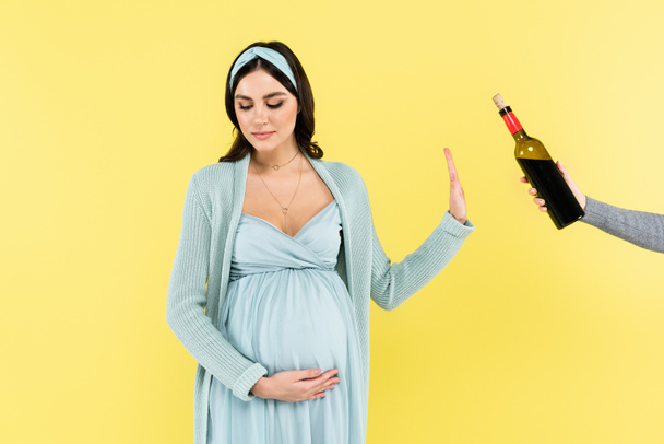 νεαρή έγκυος γυναίκα αρνείται από το κόκκινο κρασί που απομονώνονται σε κίτρινο - Φωτογραφία, εικόνα