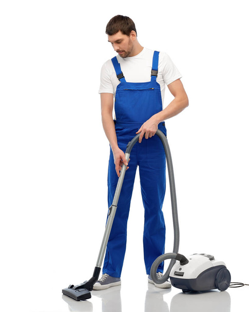 male worker cleaning floor with vacuum cleaner - Fotó, kép